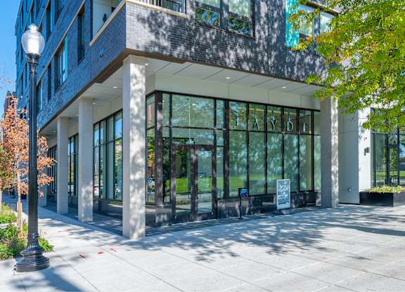 A modern building with a glass facade and a tree in front.