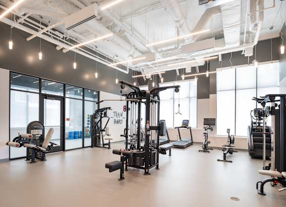 A gym with a variety of equipment including a treadmill, weights, and a stationary bike.