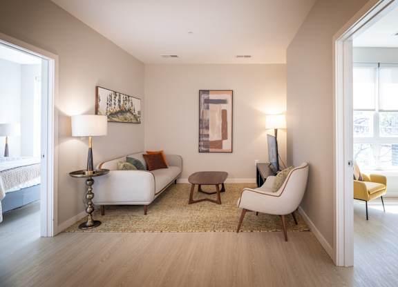 A living room with a white couch, a yellow chair, and a painting on the wall.