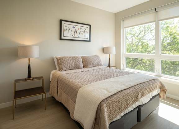 A bedroom with a large bed and a window overlooking trees.