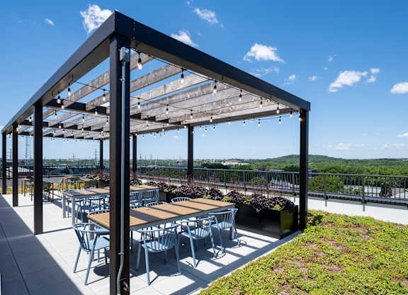 A patio with tables and chairs under a roof with a view of the water.
