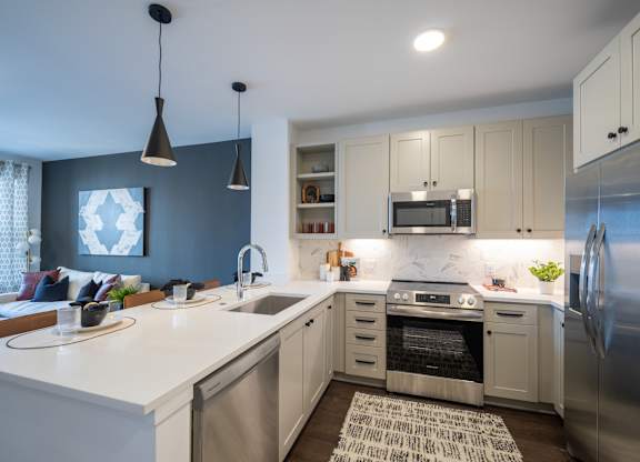 A modern kitchen with a white countertop and stainless steel appliances. at The Sully Apartments, Chantilly, VA