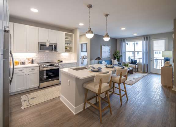 A modern kitchen with a breakfast bar and a dining area at The Sully Apartments, Virginia