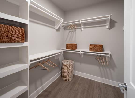 A walk-in closet with white shelves and wooden hangers at The Sully Apartments, Chantilly