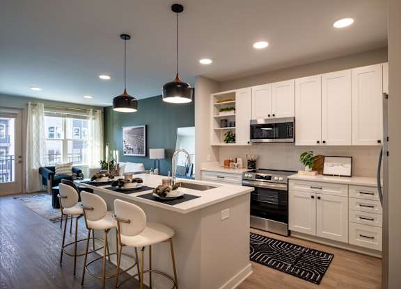 A modern kitchen with white cabinets and a large island.at The William, Virginiaa, 20152