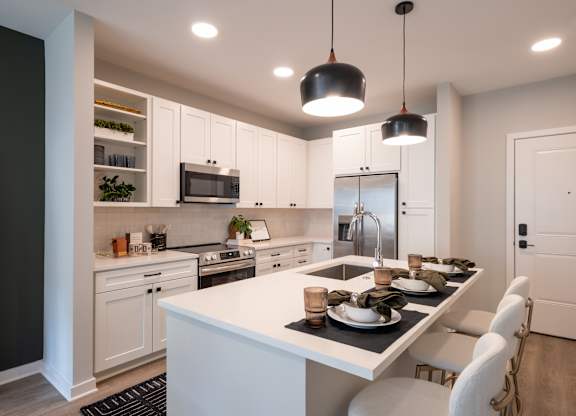 A modern kitchen with a large island and white cabinets.at The William, Chantilly, VA 20152