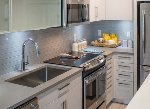 A modern kitchen with white cabinets and steel appliances. at Dock 79, District of Columbia