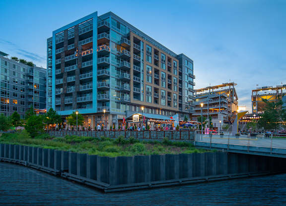 A modern building with a green roof is situated next to a body of water. at Dock 79, Washington, District of Columbia