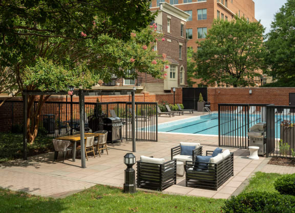 a swimming pool with chairs and tables in a courtyard