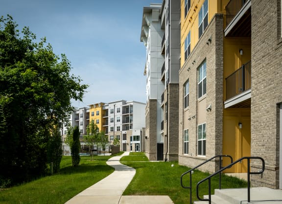 a pathway leads through a grassy area in front of an apartment building  at Woodmore Grand, Bowie