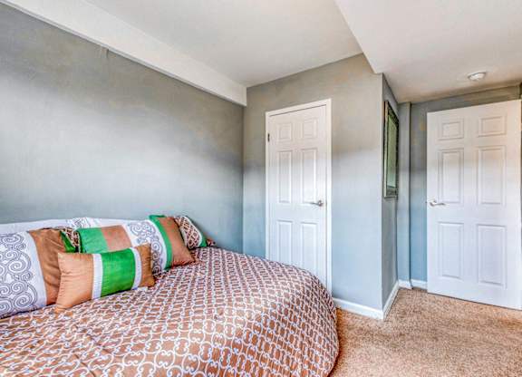 A bedroom with a bed and two doors at Huntwood Courts Apartments, Washington DC