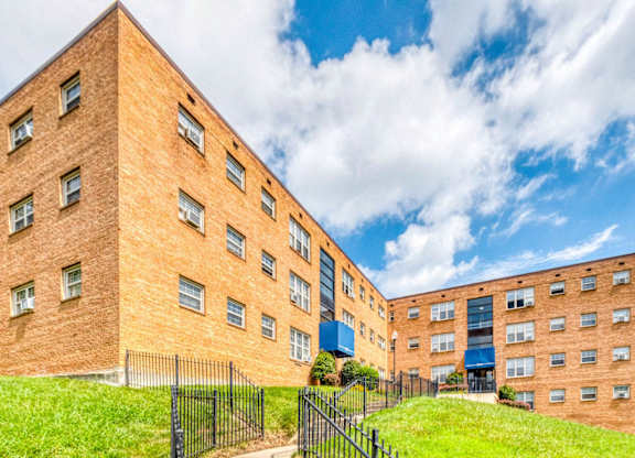 A large brick building with a black fence in front at Huntwood Courts Apartments, Washington, 20019