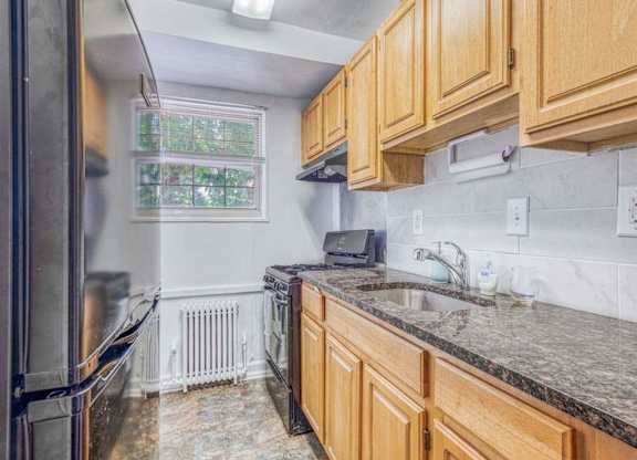 A kitchen with wooden cabinets and granite countertops at Huntwood Courts Apartments, Washington, 20019