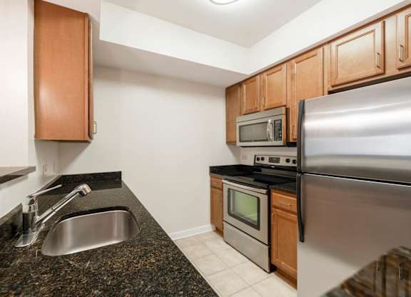 A kitchen with a stainless steel refrigerator, microwave, and oven.