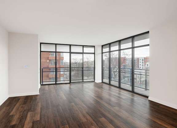 A room with wooden floors and large windows overlooking a cityscape.