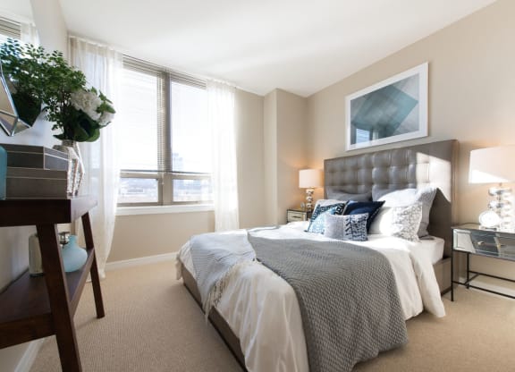 a bedroom with a large bed and two windows at The Acadia at Metropolitan Park, Arlington