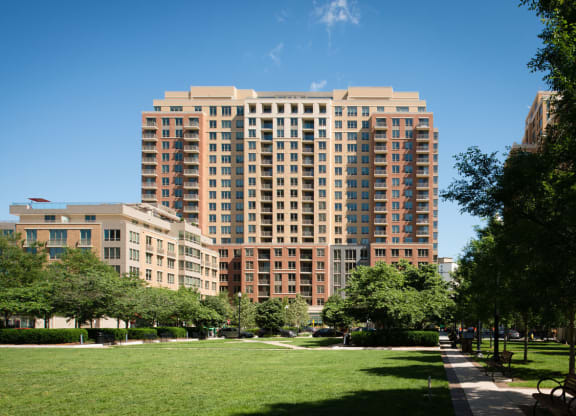 a tall building with many windows and a green park in front of it at The Acadia at Metropolitan Park, Arlington, 22202