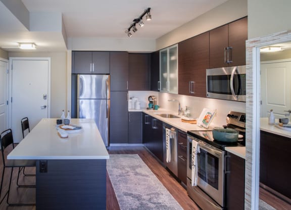 a kitchen with dark wood cabinets and white countertops at The Acadia at Metropolitan Park, Arlington, VA, 22202