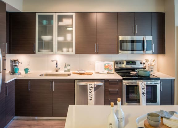 a modern kitchen with dark wood cabinets and white countertops at The Acadia at Metropolitan Park, Virginia