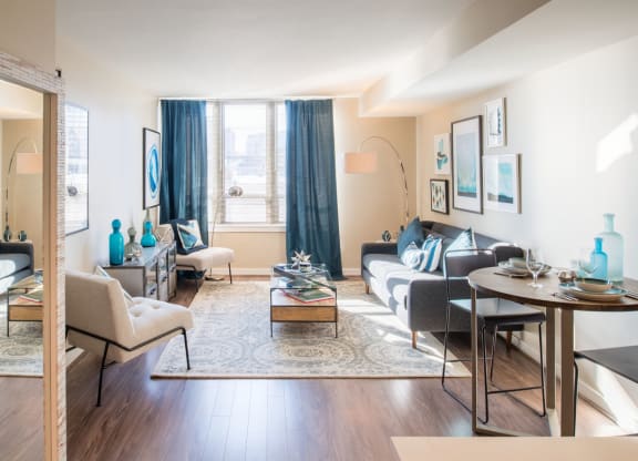 a living room with white walls and a large window with blue curtains at The Acadia at Metropolitan Park, Virginia