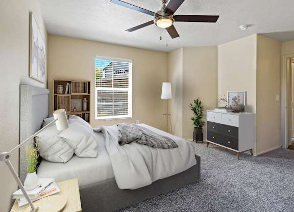A bedroom with a bed, nightstand, and a ceiling fan. at Bluffs Apartments, Bluffdale