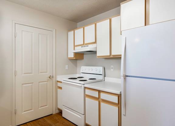 A white and gold kitchen with a white fridge. at Bluffs Apartments, Bluffdale, Utah