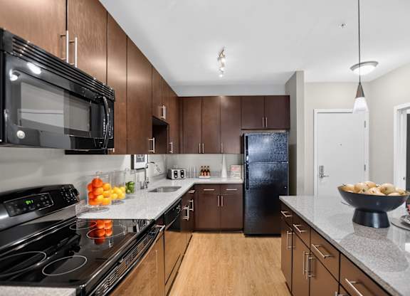 A modern kitchen with dark brown cabinets and a black microwave.
