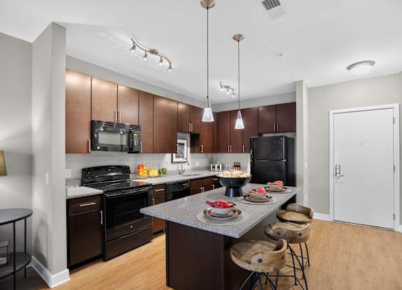 A kitchen with brown cabinets and a black refrigerator.