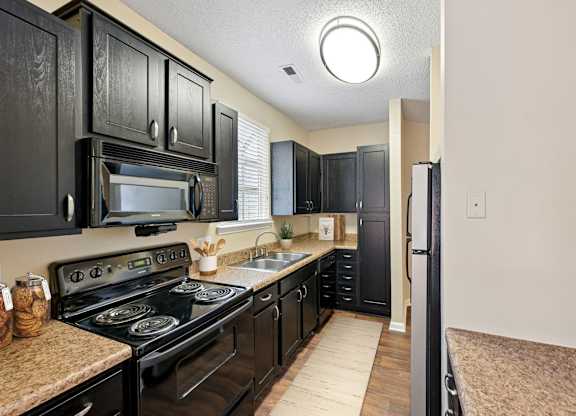 A kitchen with black cabinets and a black stove top oven.