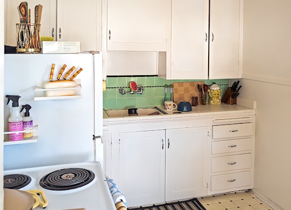 A kitchen with white cabinets and a blue refrigerator at Barbara Worth Apartments, Salt Lake City