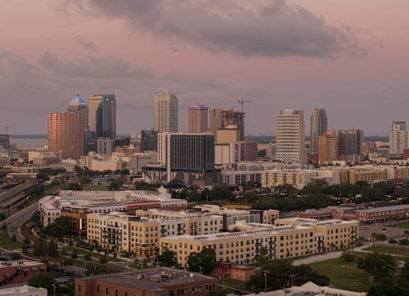 A cityscape with buildings of various heights and a cloudy sky.