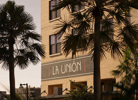 A tall building with the words "La Union" on the side is surrounded by palm trees.