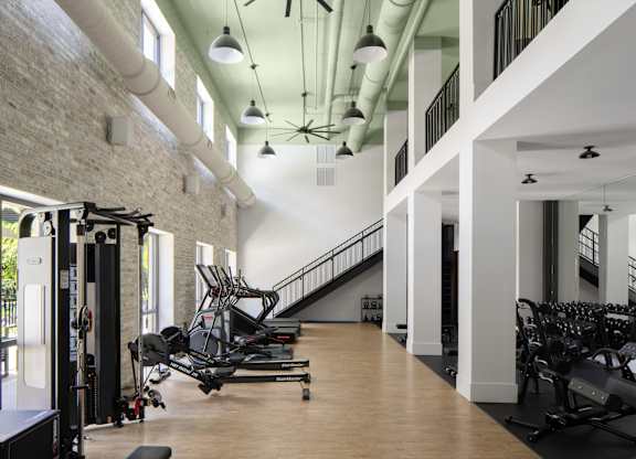 A gym with a row of treadmills and a row of stationary bikes.