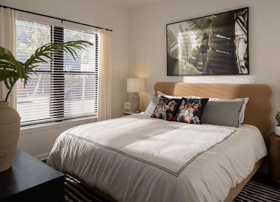 A bedroom with a large bed and a painting on the wall.