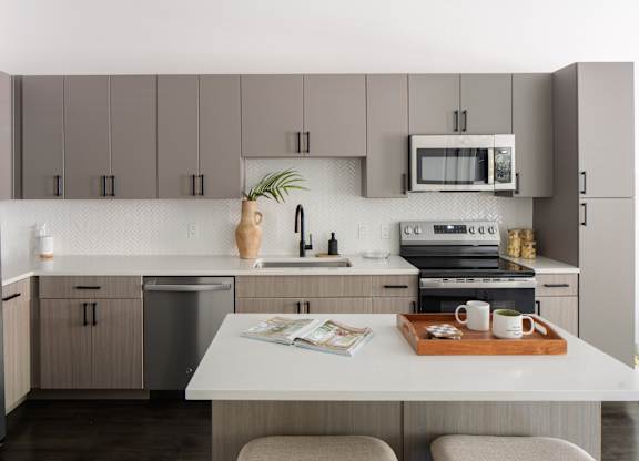 A kitchen with a white countertop and grey cabinets.