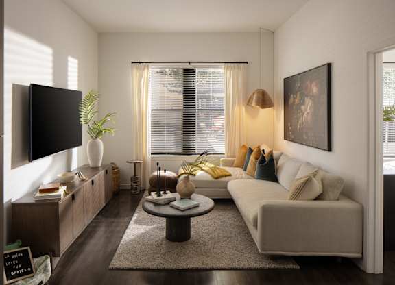 A living room with a couch, a coffee table, and a flat-screen TV.