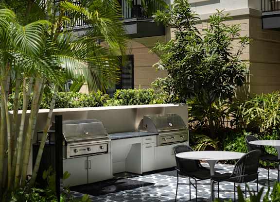 A patio with a table and chairs and a grill.