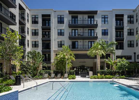 A large swimming pool in front of a multi-story apartment building.