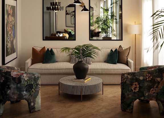 A living room with a white couch, a coffee table, and two large mirrors.