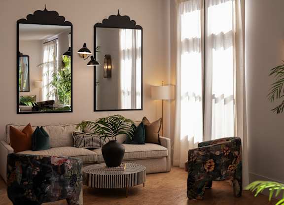 A living room with a large mirror, a sofa, a coffee table, and a potted plant.