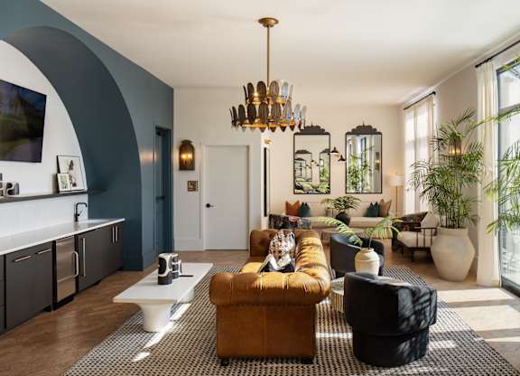 A living room with a brown couch and a chandelier.
