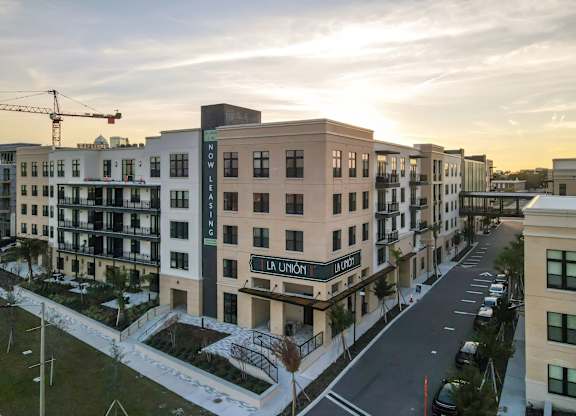 A street view of a residential area with apartment buildings and a crane in the background.