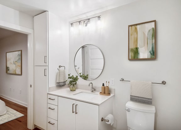 a white bathroom with a mirror and a sink at Hawkins Press Apartments, Charlotte