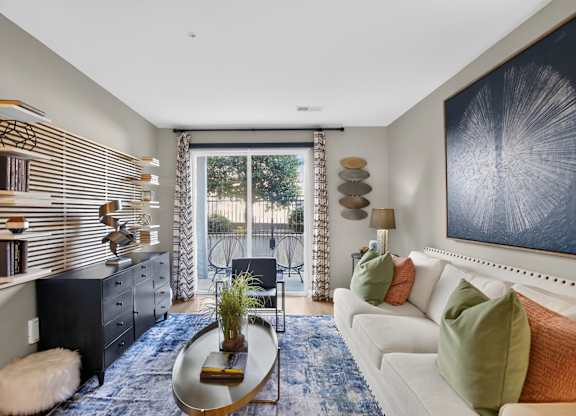 A living room with a white couch, a coffee table, and a large painting on the wall.