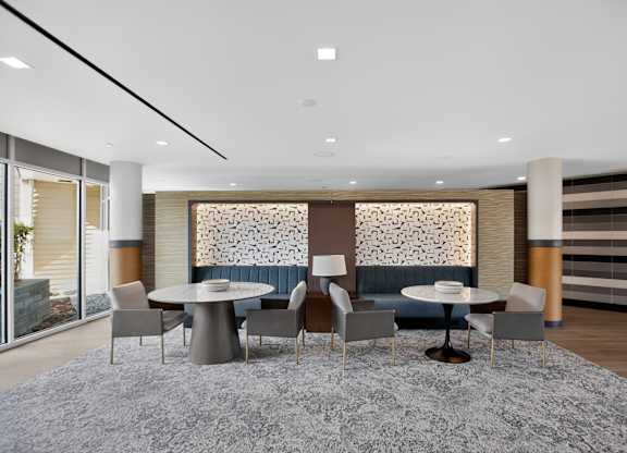 A modern dining room with a grey rug and a round table with chairs.