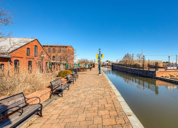 a canal with benches next to a brick walkway at North Market South Carroll, Frederick, MD