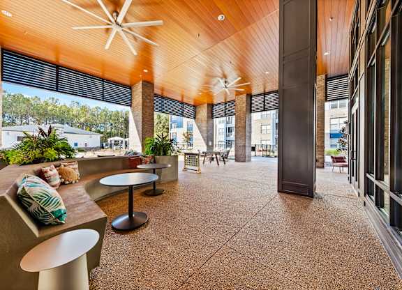 A modern outdoor seating area with a wooden ceiling and concrete flooring.