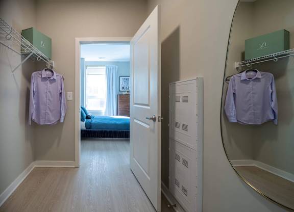 A hallway with a bedroom at the end and two shirts hanging up at Jayde Parkside Apartments, Washington, DC