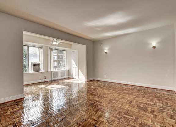 A room with wooden flooring and a window overlooking a street.
