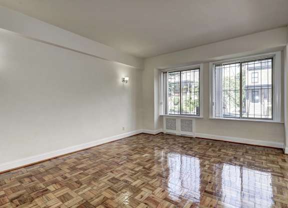 A room with a wooden floor and two windows.